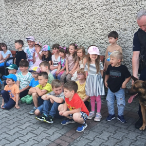 Pamiątkowe zdjęcie klasy z psem i jego przewodnikiem